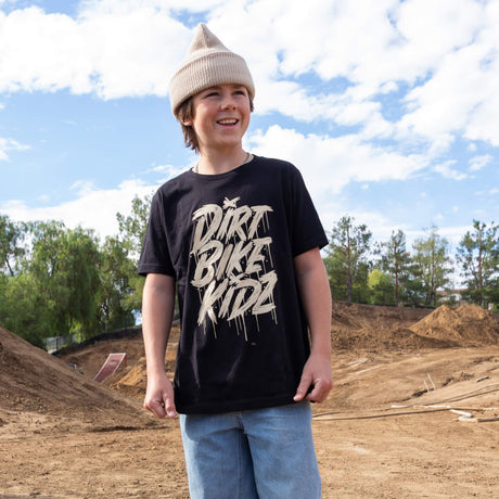 Youth black tee with beige DRRT BIKE RIDE graphic, worn with knit beanie.