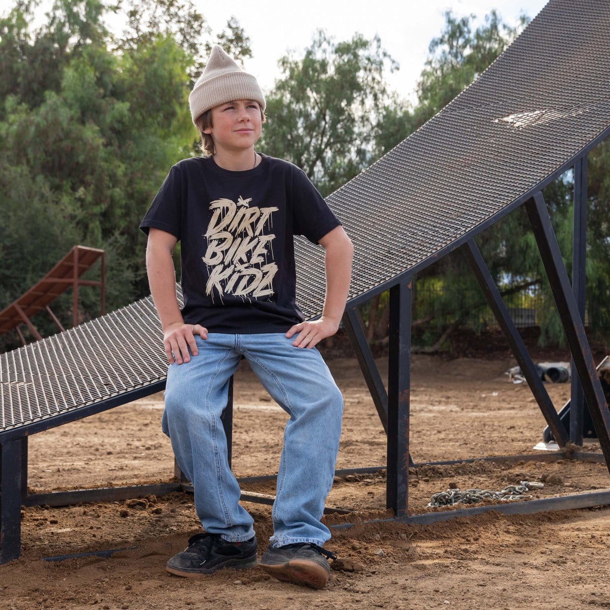 Youth black tee with beige DRRT BIKE RIDE graphic, worn with light blue jeans.