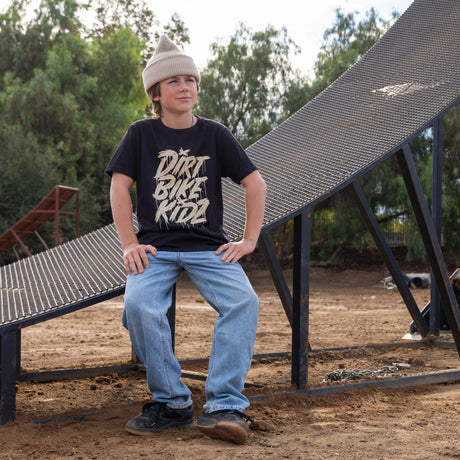 Youth black tee with beige DRRT BIKE RIDE graphic, worn with light blue jeans.