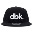 Black snapback cap front view with large white dbk logo and flat brim.