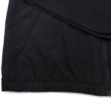 Black youth windbreaker hem close-up with elastic cuffs and visible side zipper tab