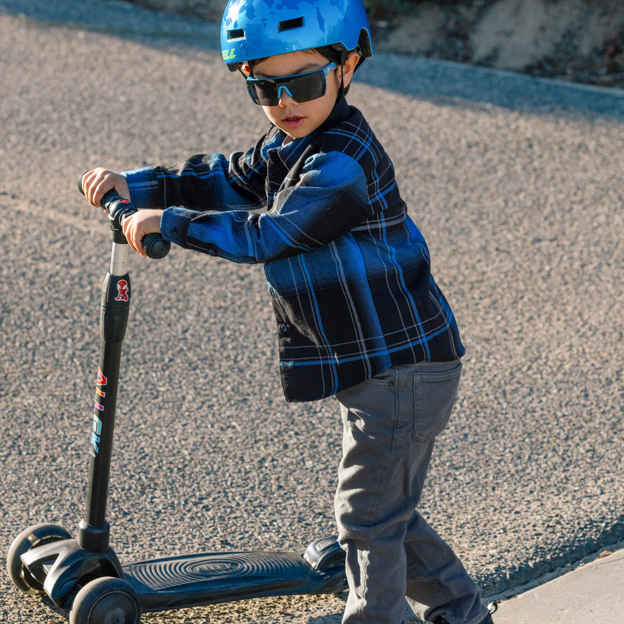 Youth flannel plaid shirt in blue and black worn while riding a scooter