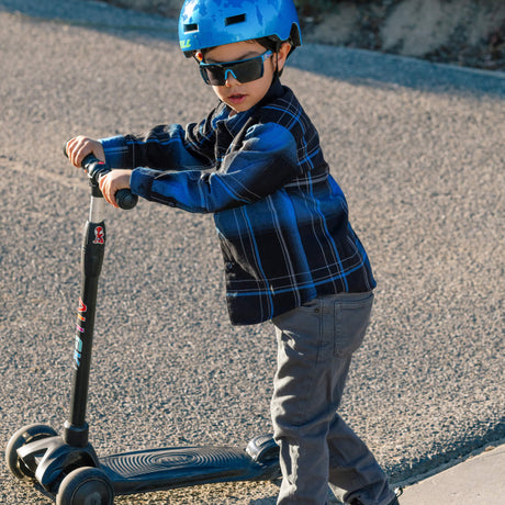 Youth flannel plaid shirt in blue and black worn while riding a scooter