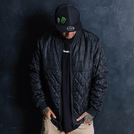 Black quilted jacket with full zipper and stand collar, worn with long sleeves