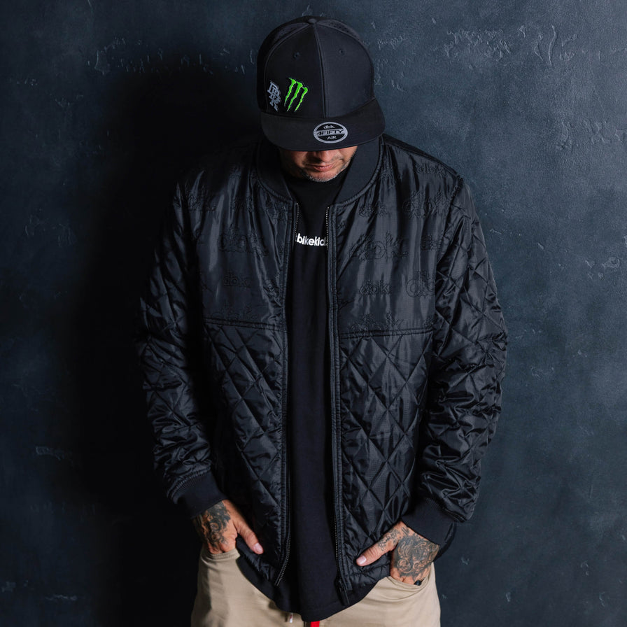 Black quilted jacket worn open with full-length zipper and high stand collar.