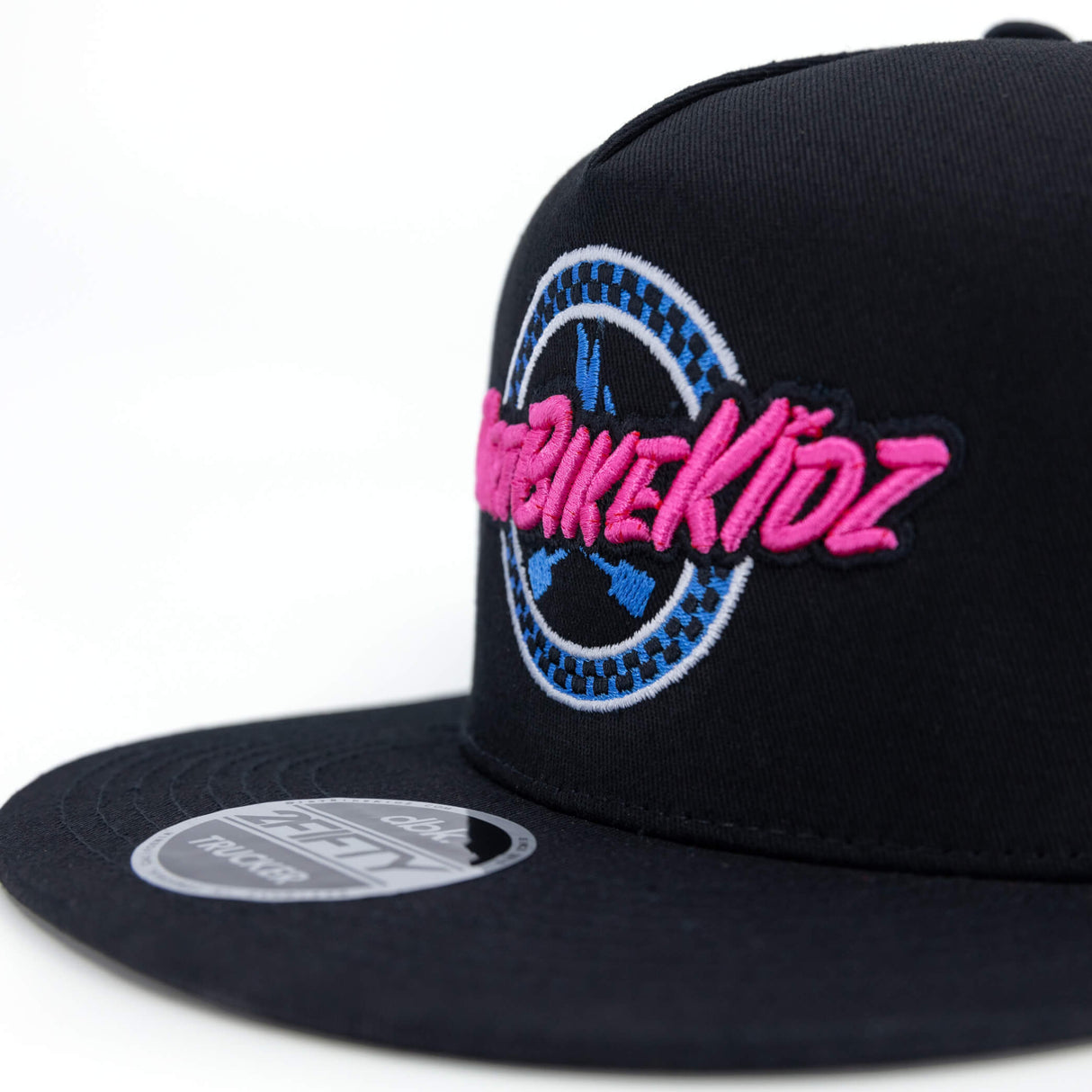 Black trucker cap side view with pink-and-blue circular logo and white brim patch