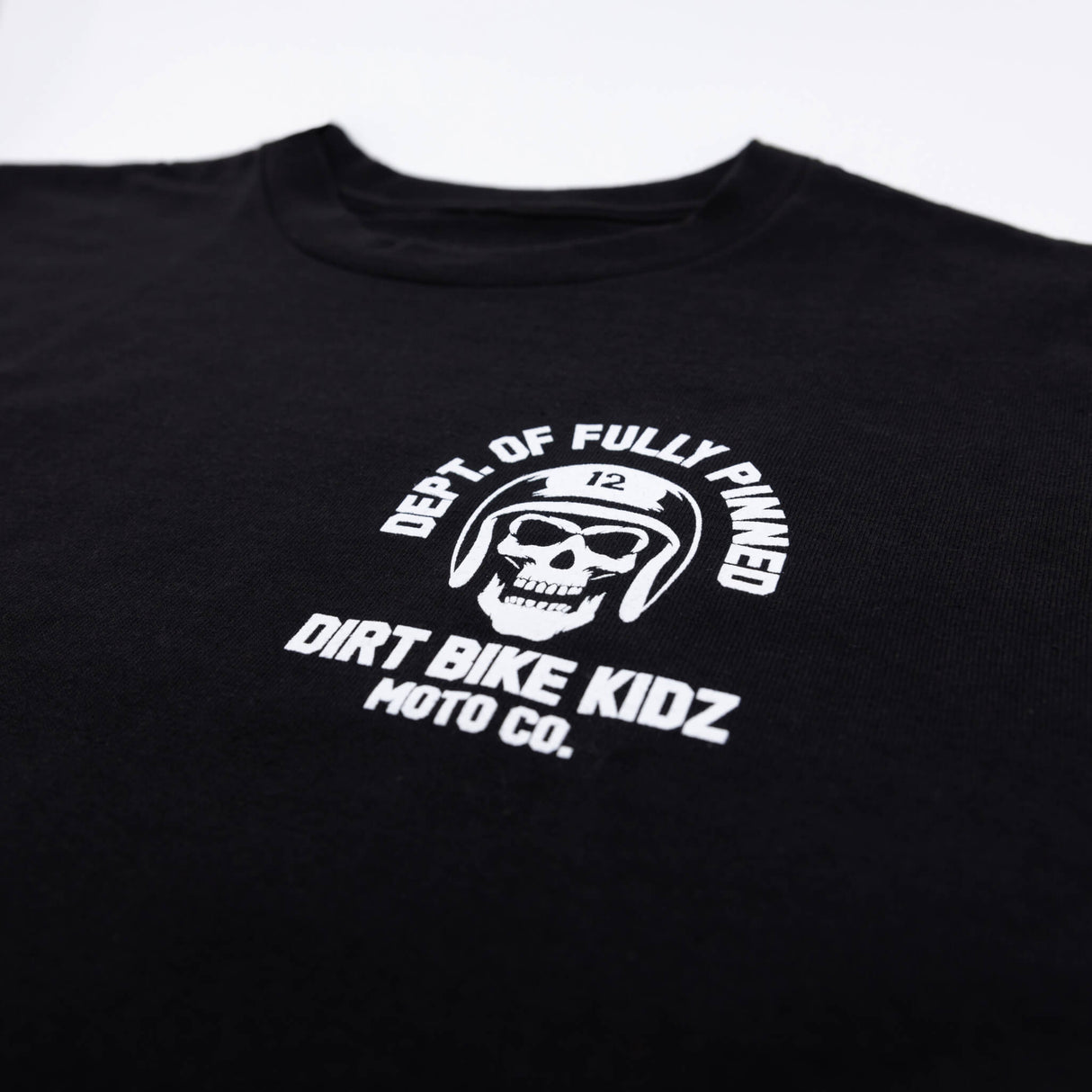 Black kids graphic tee close-up of helmet skull emblem and “Dirt Bike Kidz” text.