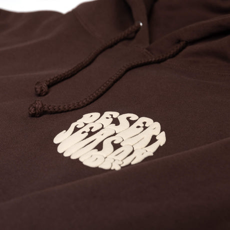 Close-up of dark brown hoodie drawstrings and small white logo on the front