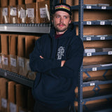 Navy hoodie worn with hood up; front cross logo and kangaroo pocket.