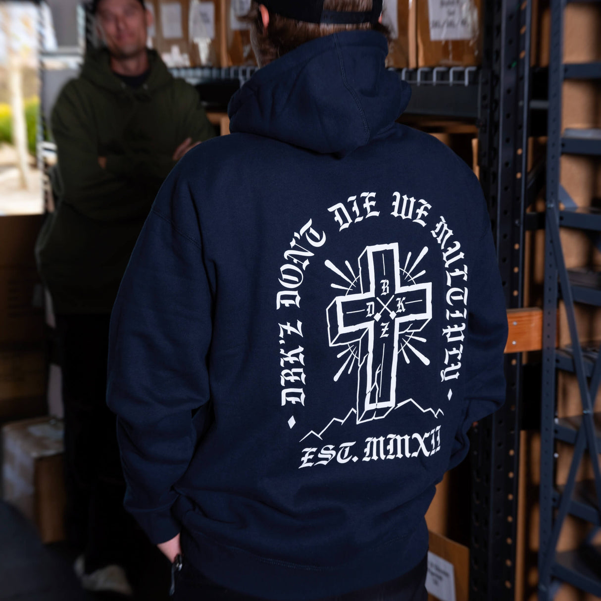 Navy hoodie back view with large white cross graphic and lettering, hood and pocket.