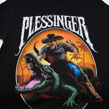 Black youth T-shirt close-up of “Blessinger” and illustrated cowboy riding a crocodile.