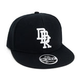 Black youth snapback cap with white monogram-style graphic and oval Youth patch
