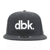 Charcoal snapback cap with large white dbk logo centered on the front