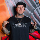 Black dbk graphic T-shirt worn by man with cap and gold chain