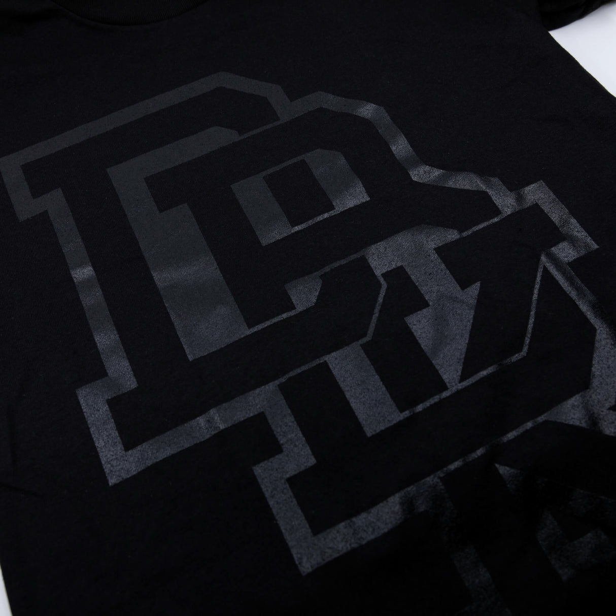 Pitch Black T-shirt close-up: black with large gray letter graphic detail
