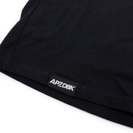 Youth T-shirt hem with small 'AP7DBK' brand label on black fabric