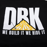 Black crewneck T-shirt close-up: white DRK letters over yellow mountain graphic