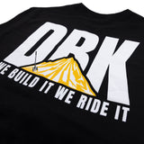 Black crewneck T-shirt close-up of diagonal 'WE BUILD IT WE RIDE IT' over DRK