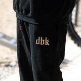 Black premium sweatpants with small gold logo print on the leg