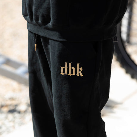 Black premium sweatpants with small gold logo print on the leg