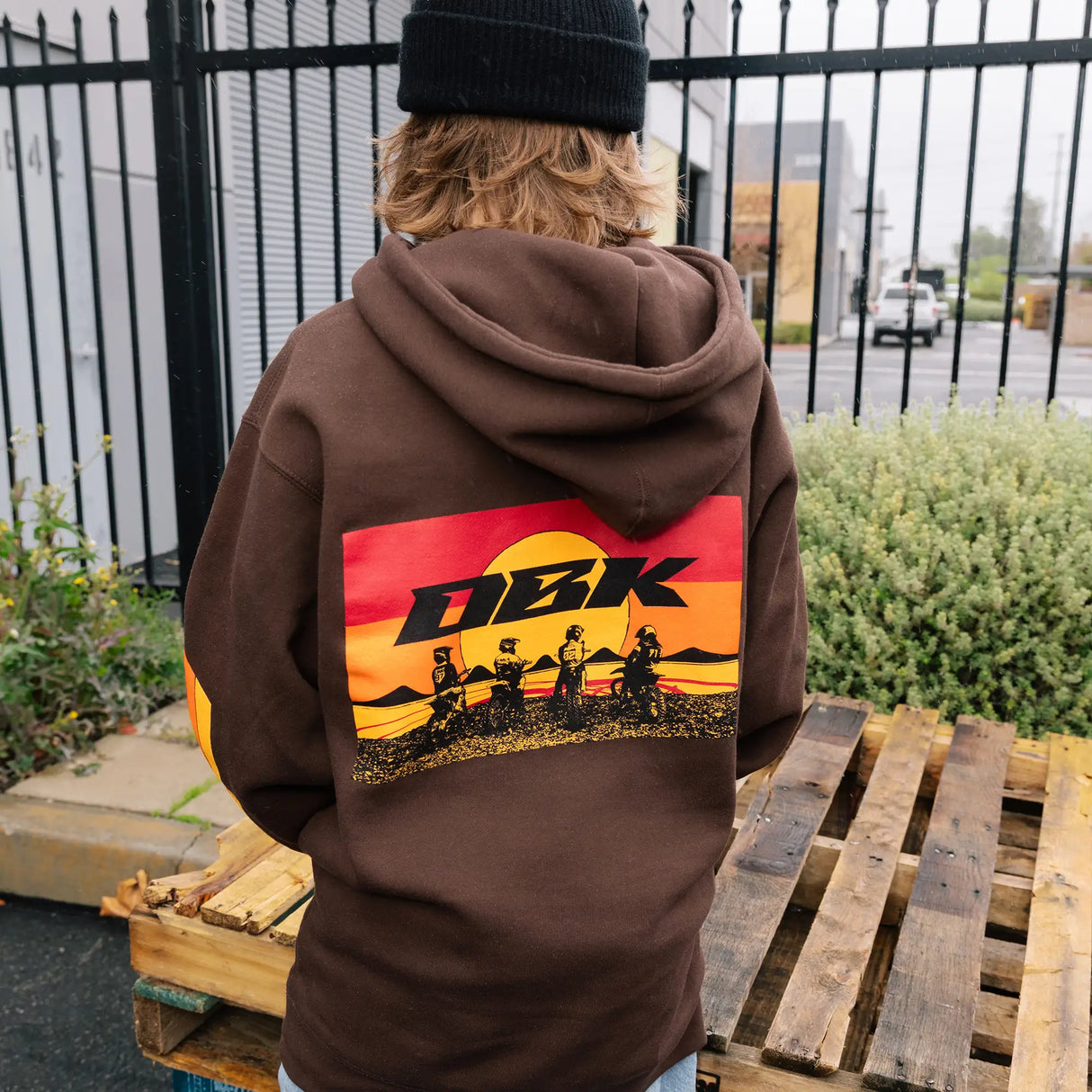 Brown youth hoodie with back graphic, drawstring hood, and colorful sleeve stripes