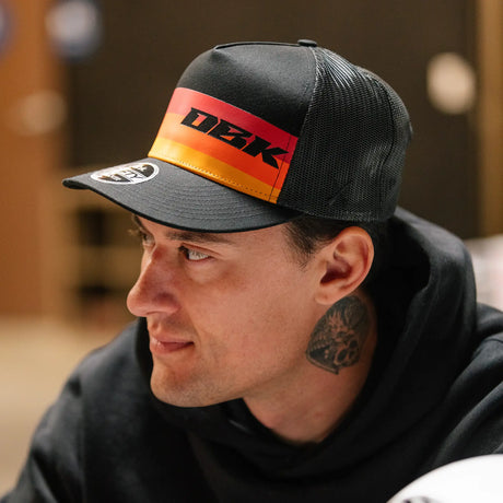 Trucker cap with DBK logo front panel, black mesh back and orange-red stripe