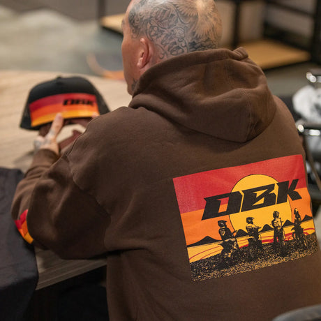 Dark brown hoodie back graphic with DBK logo and rider scene, with drawstring hood