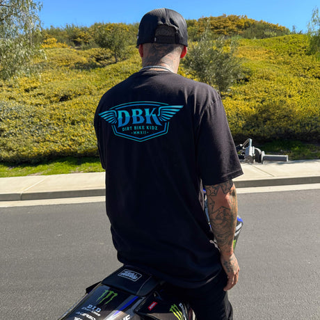 Black T-shirt, back view, with blue DBK logo graphic centered.