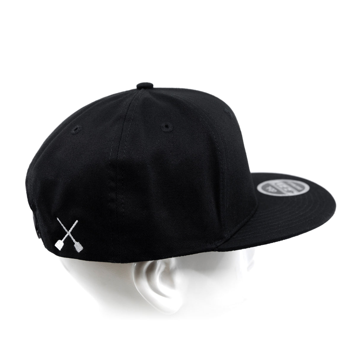 Black snapback cap on head form, showing side panel and white X logo