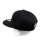Black snapback cap from side angle with curved brim and crown seams.