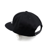 Black snapback cap from back-right angle with adjustable strap panel.