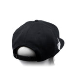 Black snapback cap with curved brim and white embroidered side graphic