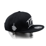 Black snapback cap with curved brim, white hand emblem, and bold side lettering