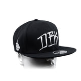 Black snapback cap with white DBK logo and small left-side emblem