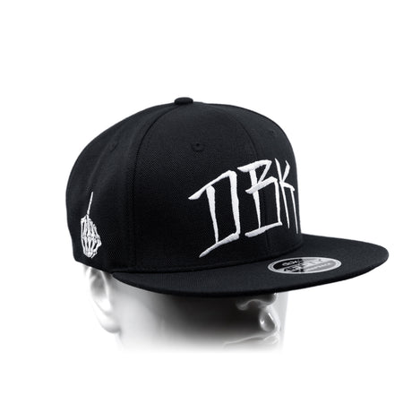 Black snapback cap with white DBK logo and small left-side emblem