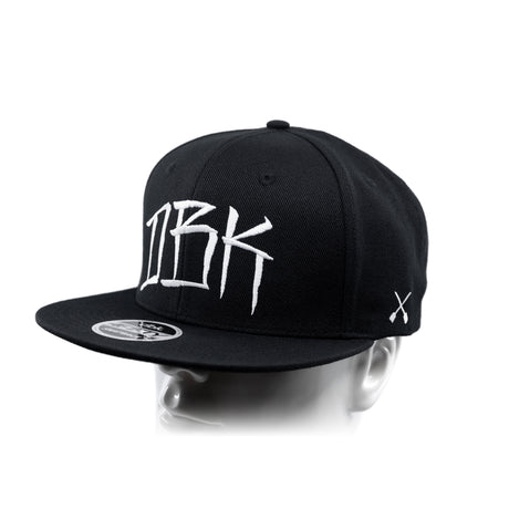 Black baseball cap with white 'DBK' logo and small white X graphic on the side