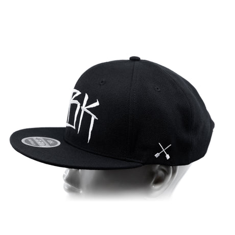 Black baseball cap with white crossbones graphic; side profile view