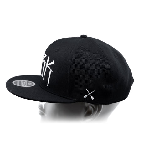 Black baseball cap with white 'DBK' lettering on the side and white crossbones graphic