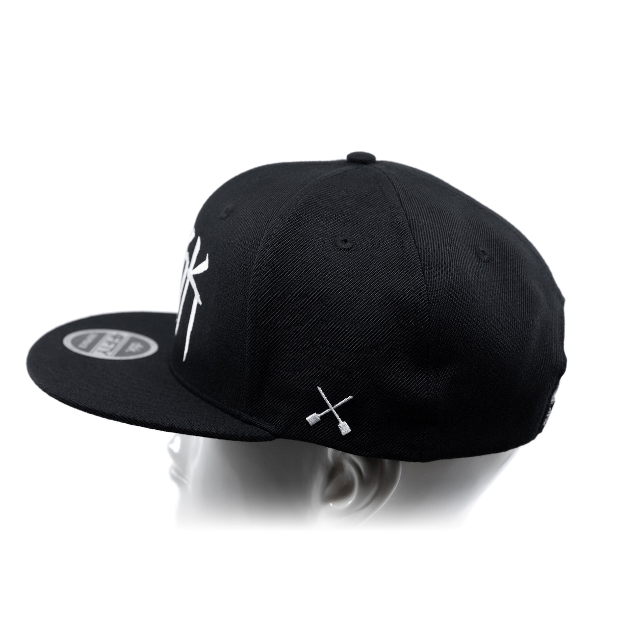 Black baseball cap showing top panels and white crossbones graphic on the side