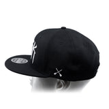 Black baseball cap showing top panels and white crossbones graphic on the side