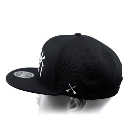 Black baseball cap showing top panels and white crossbones graphic on the side
