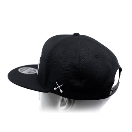 Black baseball cap with white crossbones logo and side panel view