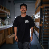 Black T-shirt with small white globe logo on left chest worn by model
