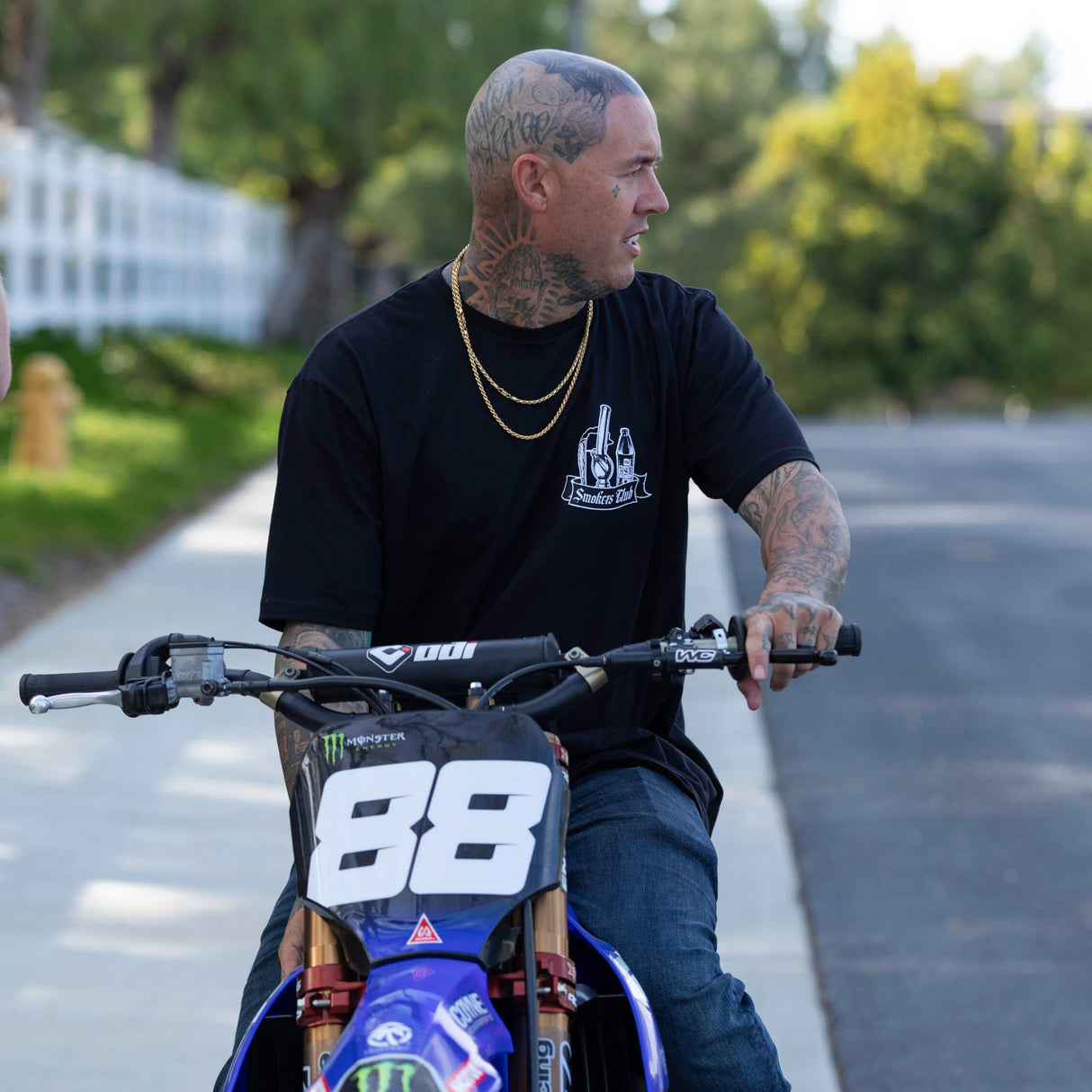 Black T-shirt with Smokes Club bottle logo on chest worn while riding a bike