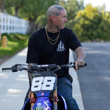 Black T-shirt with Smokes Club bottle logo on chest worn while riding a bike