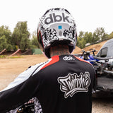Motorcycle helmet on rider, white with black graphics and red stripe, front view