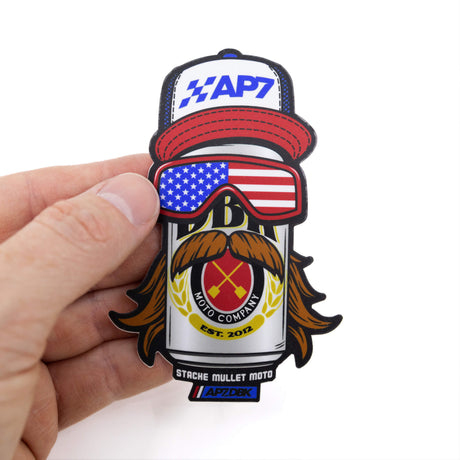 Sticker held in hand, with AP7 cap, American flag goggles, and laurel rider mustache