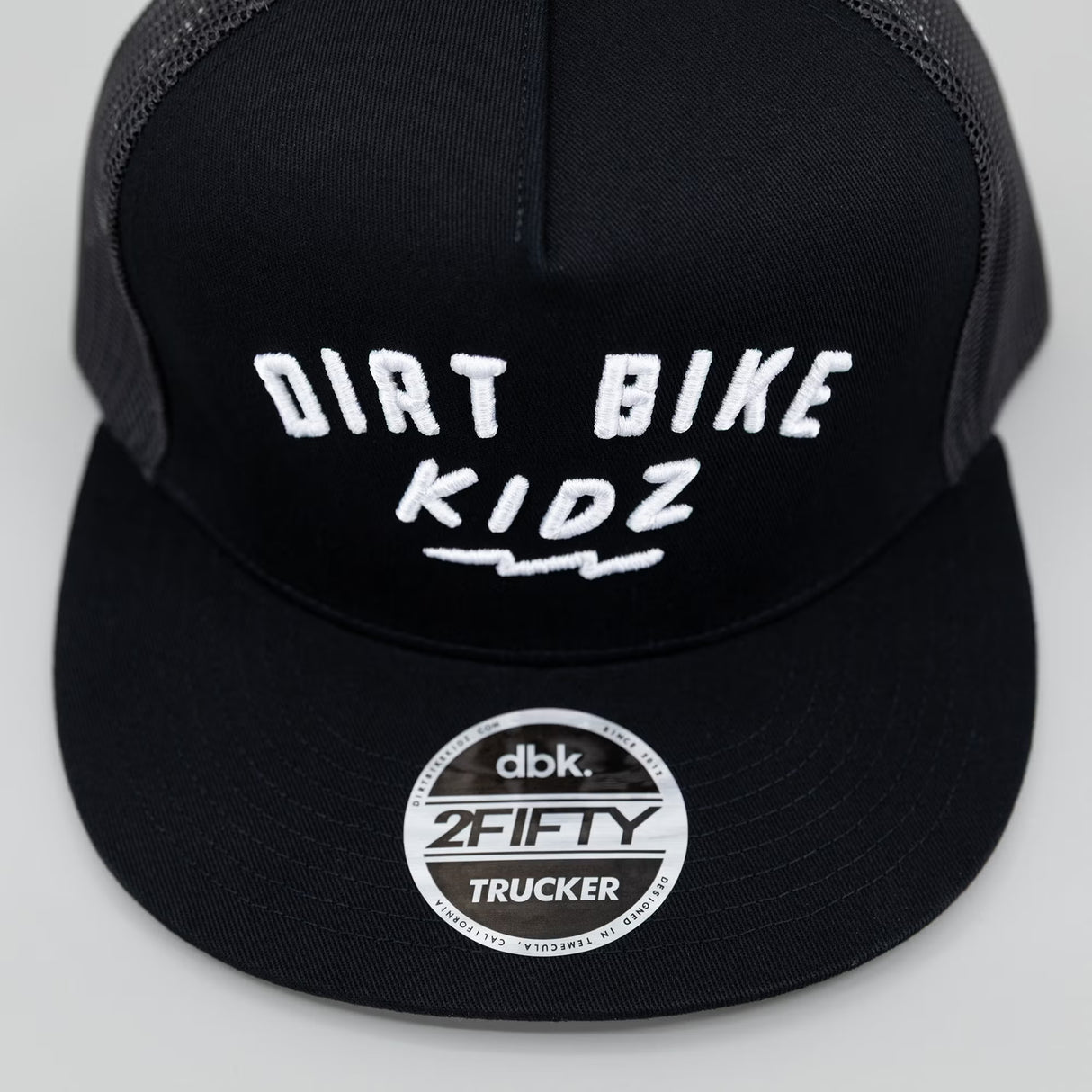 Black trucker cap with white 'DIRT BIKE KIDZ' graphic and '2FIFTY TRUCKER' badge