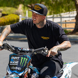 Black trucker cap with yellow DBKR wing logo on front, worn outdoors
