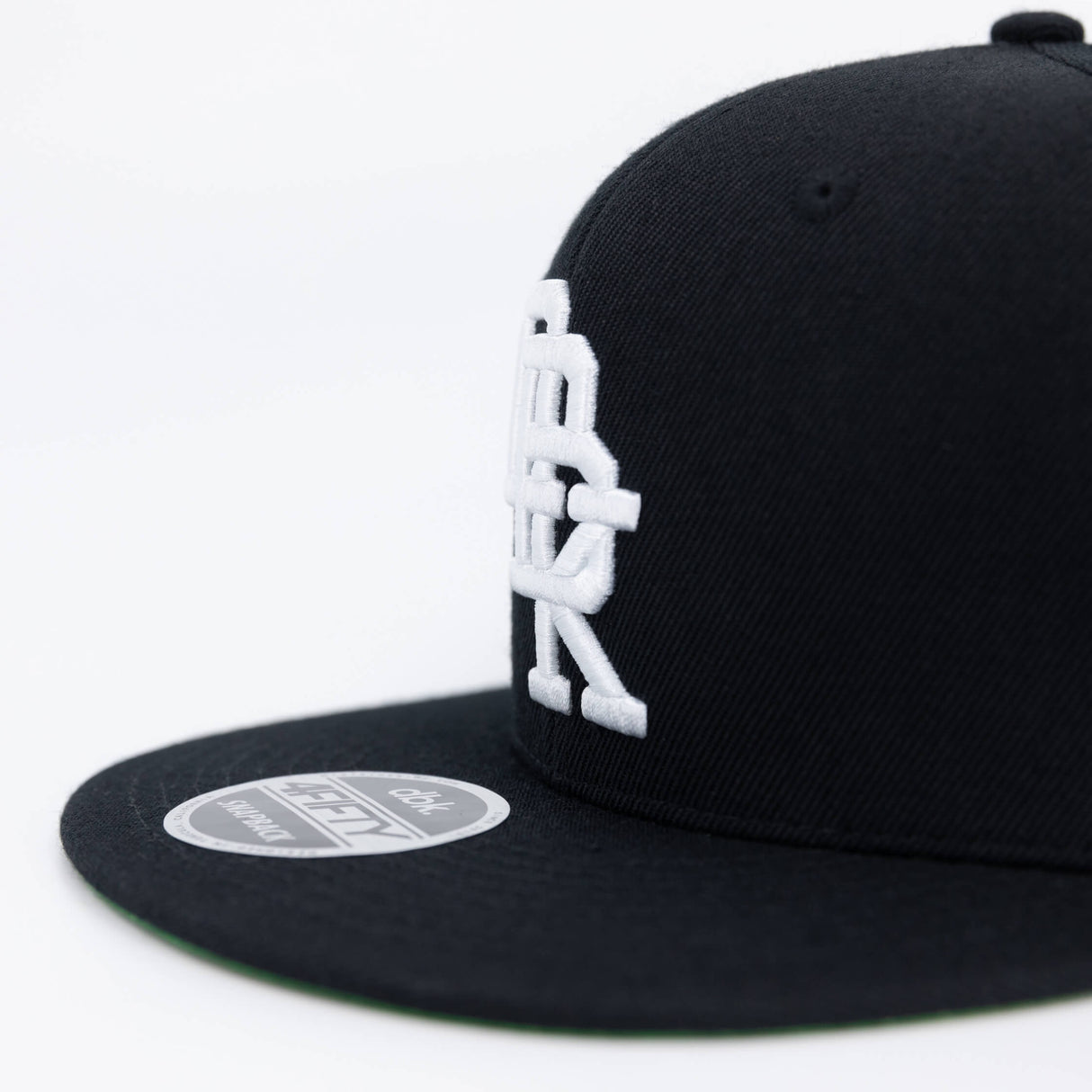 Black snapback cap side view with large white DBK logo and round 4FIFTY patch.